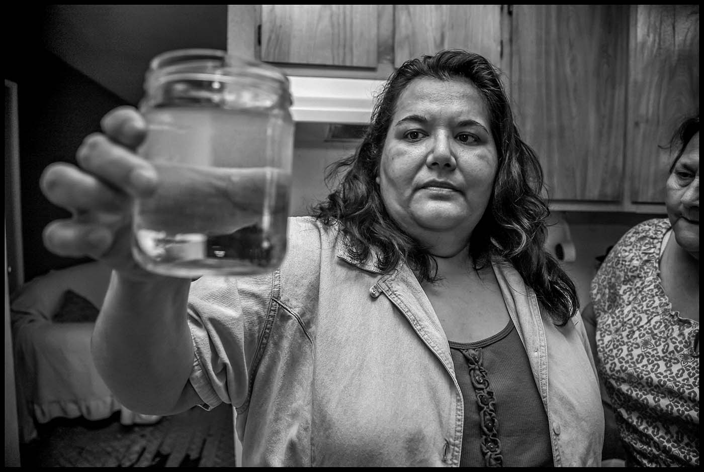 Eunice Martine holds a glass of water from the tap that she was afraid to drink.