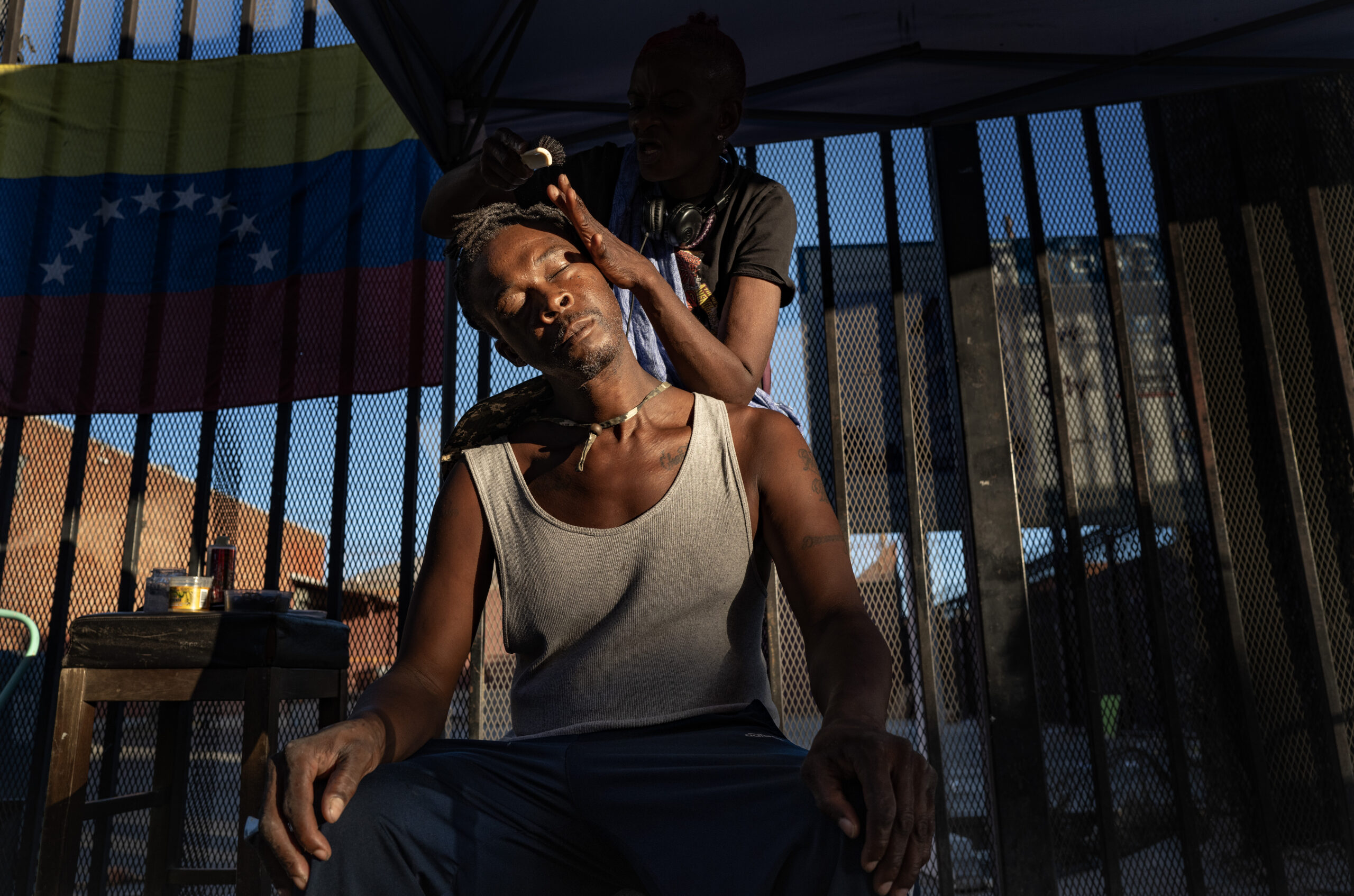 Torrell (first name only) has his cornrows styled, along the sidewalk, by La Sharron aka Chocolaté.