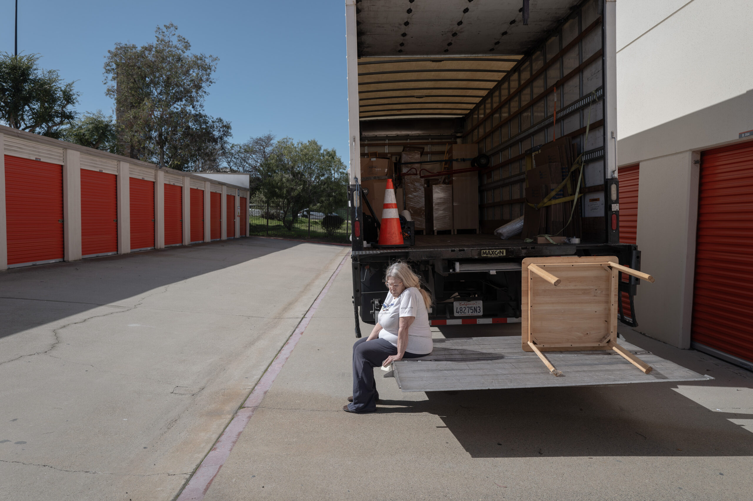 Erickson, in physical pain and unable to stand for very long, sits on the moving truck waiting for the movers to unload her belongings.